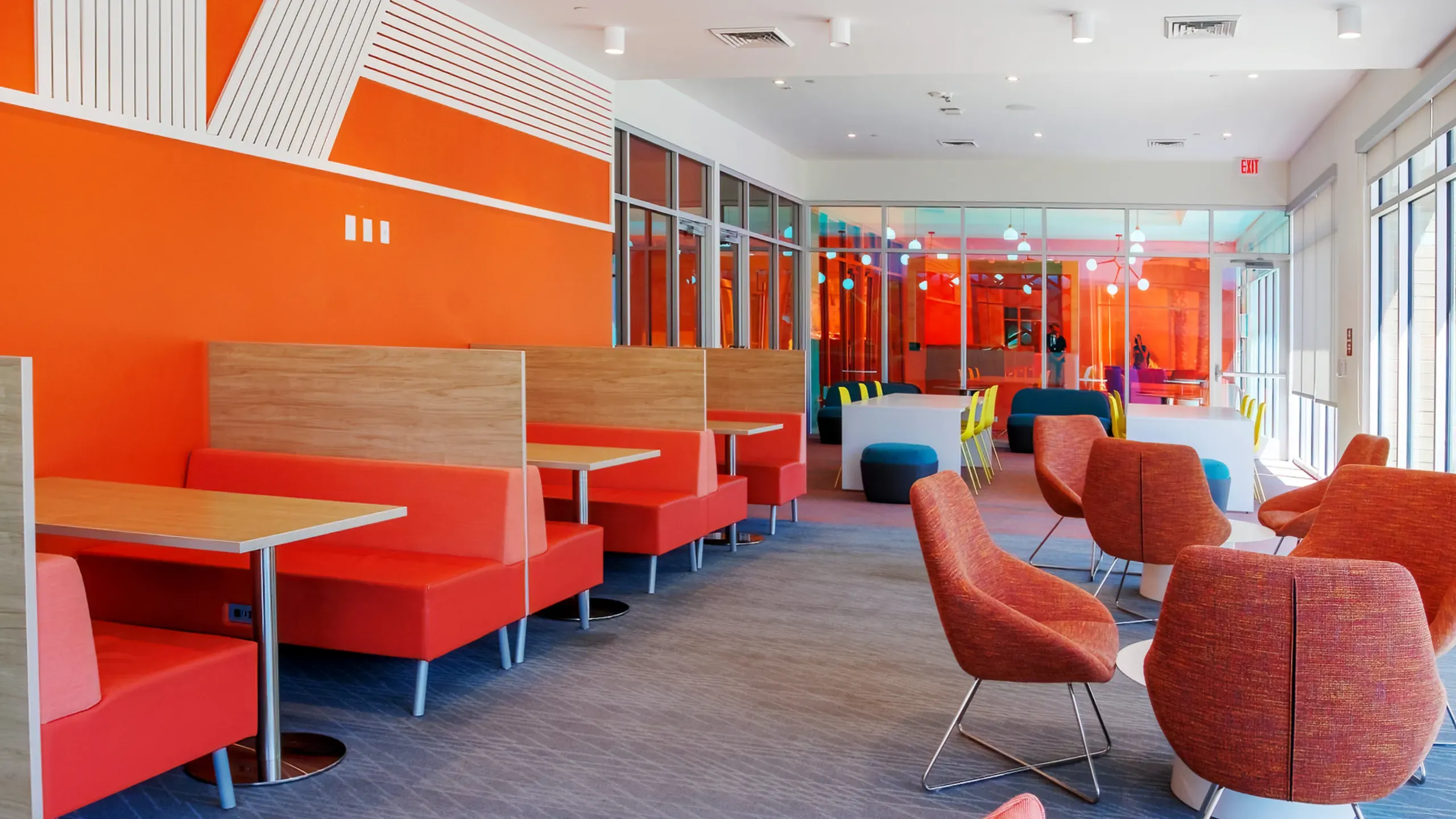 Lounge with orange booths, red chairs, and colorful murals